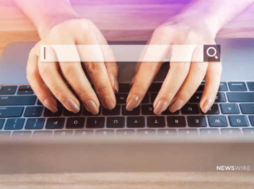Picture of a woman's hands with light brown painted fingernails on a MacBook keyboard with a search engine search bar overlayed. Image is being used for a Newswire blog about SEO and press release distribution.