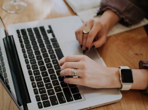 Picture of a woman typing on a laptop. Image is being used for blog post titled, Build Brand Awareness With Press Release Distribution