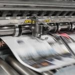 Picture of newspapers being printed. Image is being used for a Newswire blog titled, " The News Never Stops. Stand Out With Press Release Distribution Software."