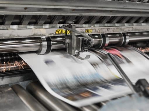 Picture of newspapers being printed. Image is being used for a Newswire blog titled, " The News Never Stops. Stand Out With Press Release Distribution Software."