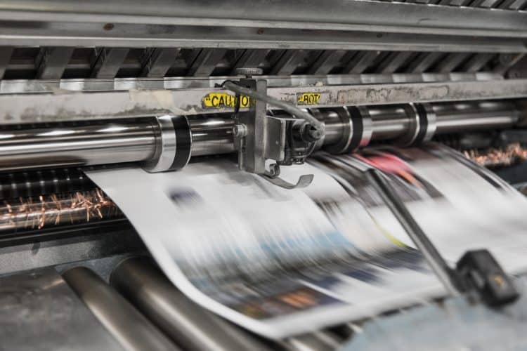 Picture of newspapers being printed. Image is being used for a Newswire blog titled, " The News Never Stops. Stand Out With Press Release Distribution Software."