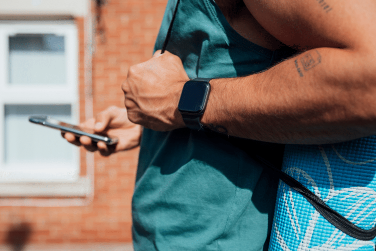 Picture of a man in a blue shirt wearing fitness gear, reading his mobile phone. Image is used for blog titled, "Newswire Helps Land Wall Street Journal Feature for Tech Industry Client"