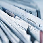 Picture of newspapers and the focus of the picture is on the word, "Business." Image is being used for a blog about earned media mentions for a health tech company.