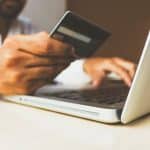 Picture of a person making a payment on their laptop, holding a credit card. Image is being used for a blog post about FeatherPay and healthcare payments.