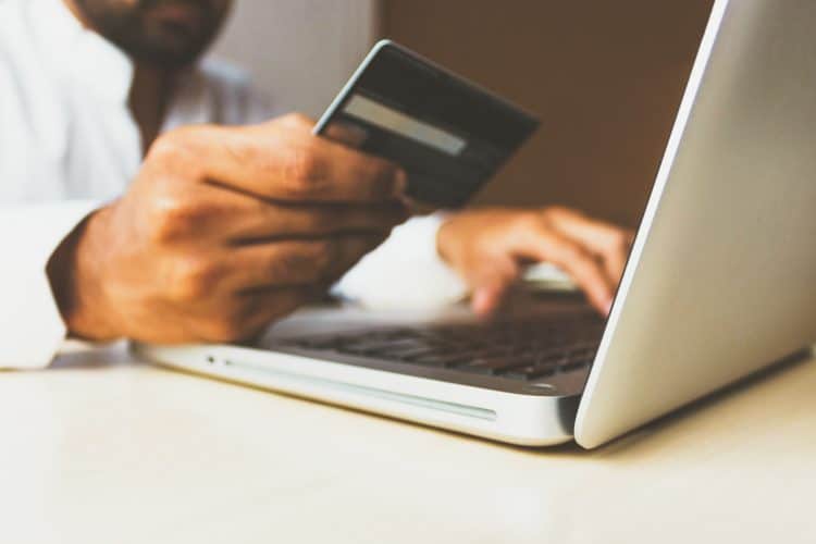 Picture of a person making a payment on their laptop, holding a credit card. Image is being used for a blog post about FeatherPay and healthcare payments.
