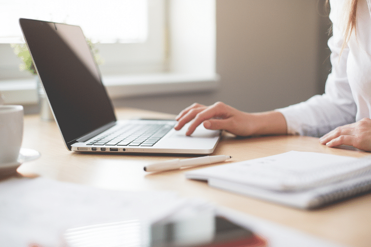 Image of a woman in a white shirt who has her hand on a laptop. Image being used for a blog about press release distribution benefiting companies of all industries.