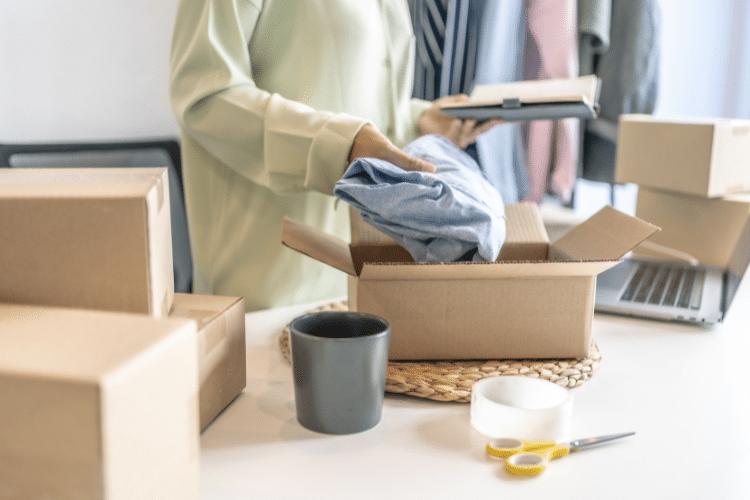 Image of a lady packing a piece of clothing into a shipping box. Image is being used for a product launch press release blog.