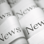 Picture of folded newspapers with the word "News" written on each headline. Image is being used for a Newswire blog titled, "Press Release Headlines Don't Have to be Boring."