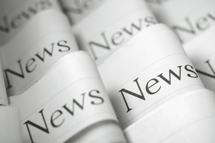 Picture of folded newspapers with the word "News" written on each headline. Image is being used for a Newswire blog titled, "Press Release Headlines Don't Have to be Boring."
