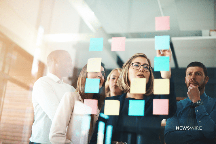 Picture of people strategizing with Post-In notes on a glass wall. Picture is used for a Newswire blog about pillar content and turning press releases into social media posts.