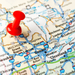 Close-up image of the state of Michigan on the map. A red thumbtack is placed on the state of Michigan. Image is being used for a Newswire blog post about the top media outlets in Michigan.