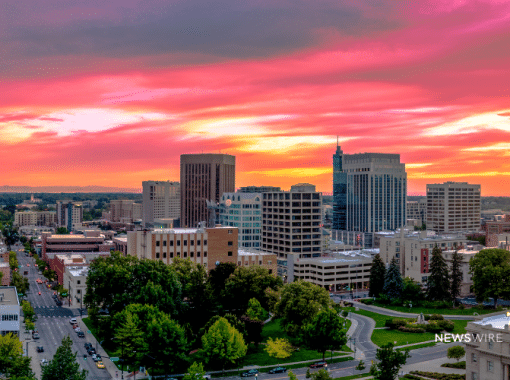 Picture of downtown Boise with a beautiful pink, yellow, and orange sky. This image is being used for a Newswire blog post about the top media outlets in Idaho.