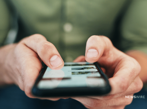 Picture of a guy holding a smart phone looking at the internet. Image is being used for a Newswire blog post about the important of press release distribution in the age of social media.