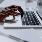 Newswire-branded image of an African American woman typing on a Macbook.